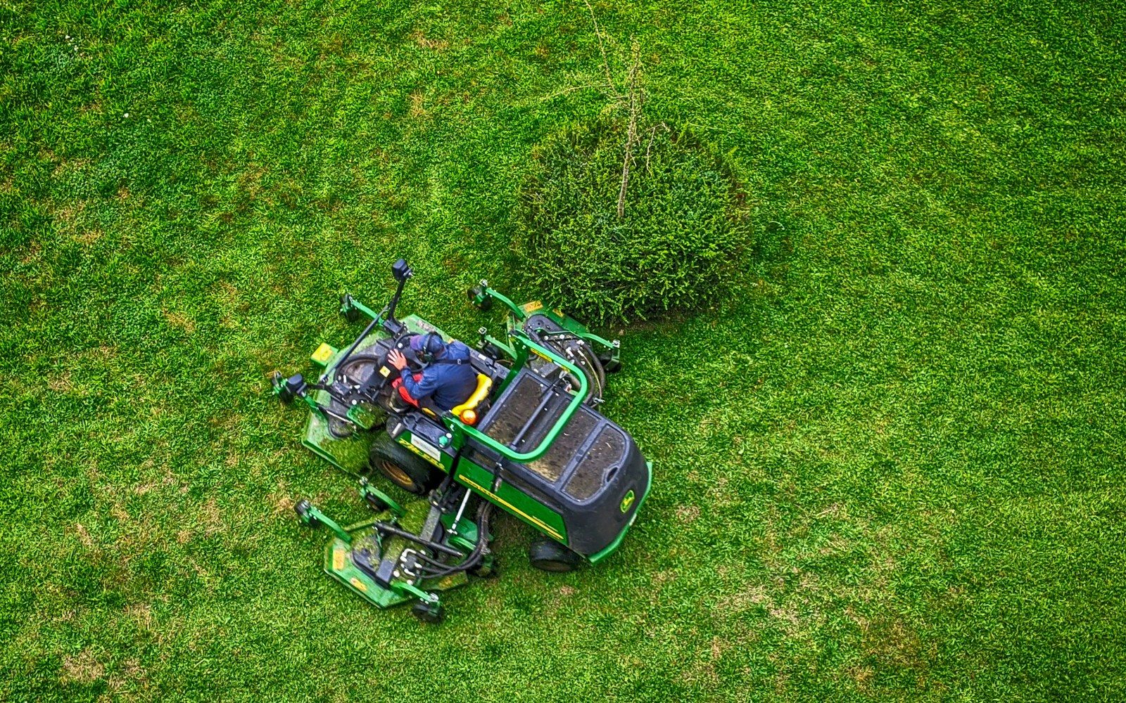 green and black ride on lawn mower on green grass field during daytime